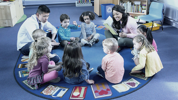 Children and teachers in a classroom sat in a circle