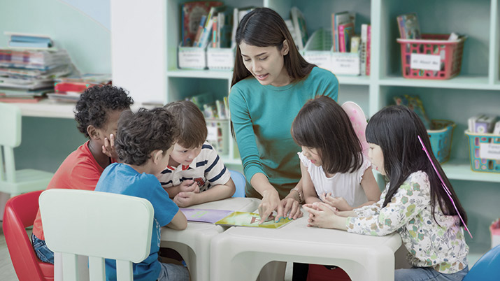 Teacher sits with a group of school children